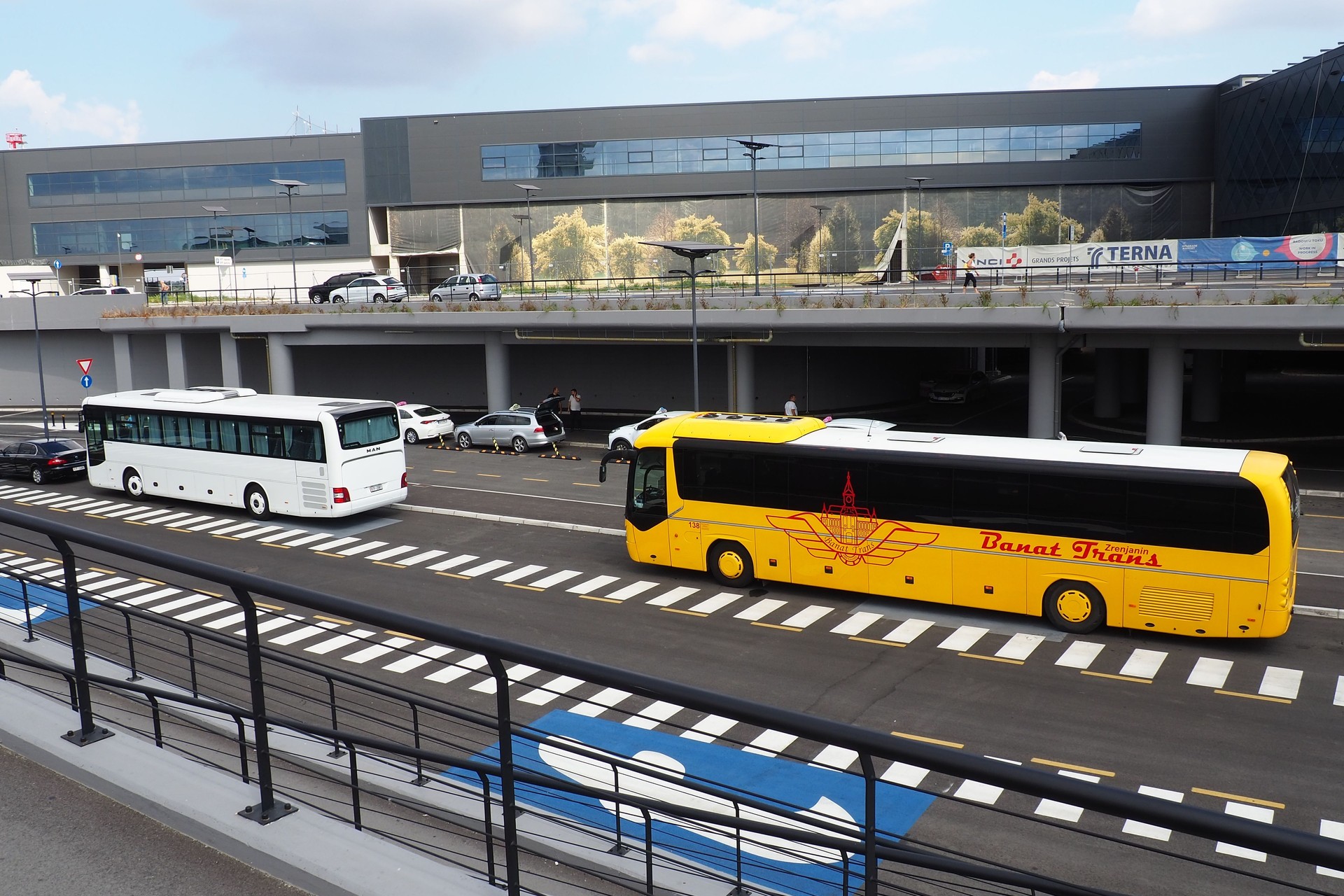 New airport buildings. Increase in passenger traffic flying by plane. Cars, people, bus station, parking. Glass airport walls.