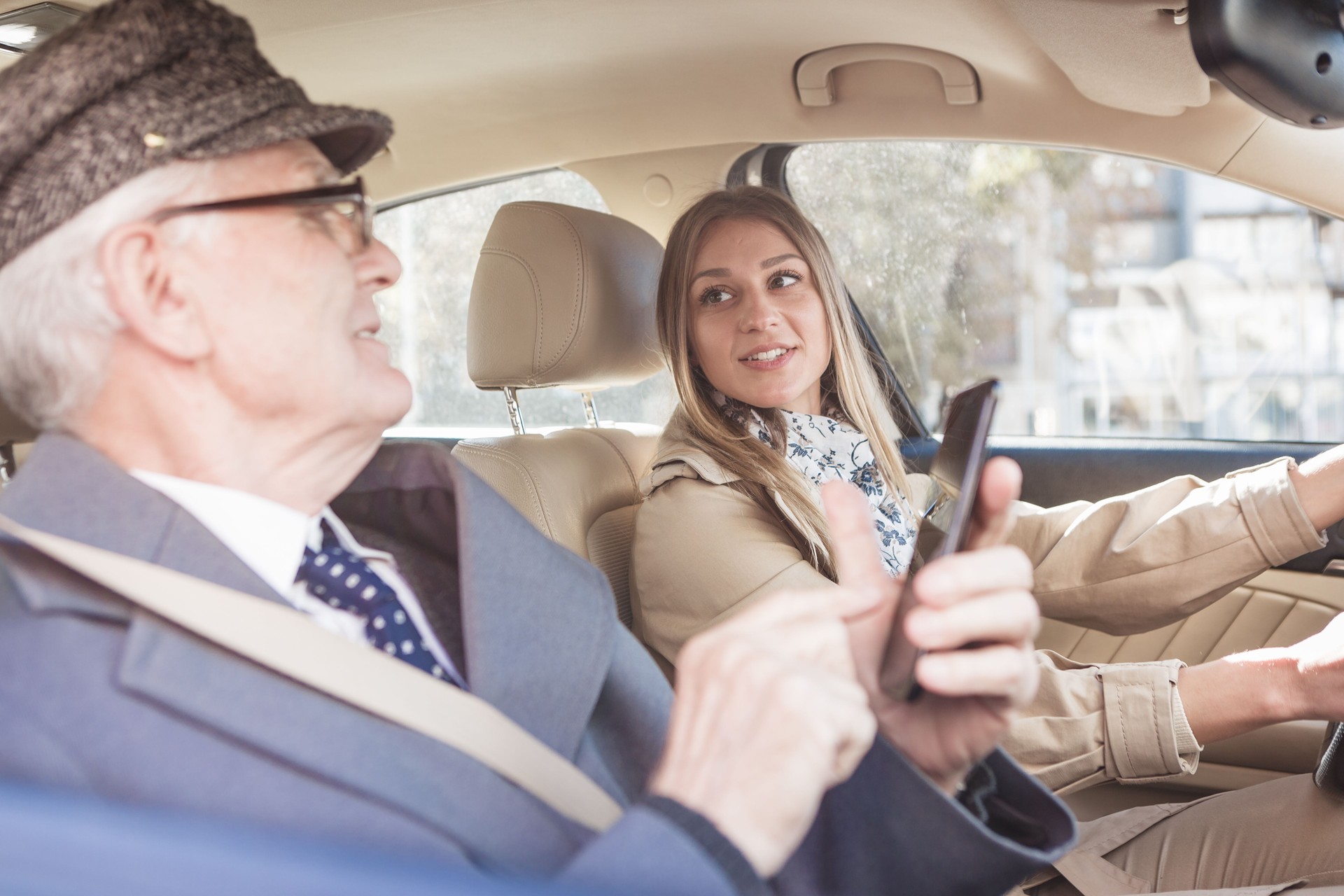 Grandfather and granddaughter driving by the car. He is using mobile phone