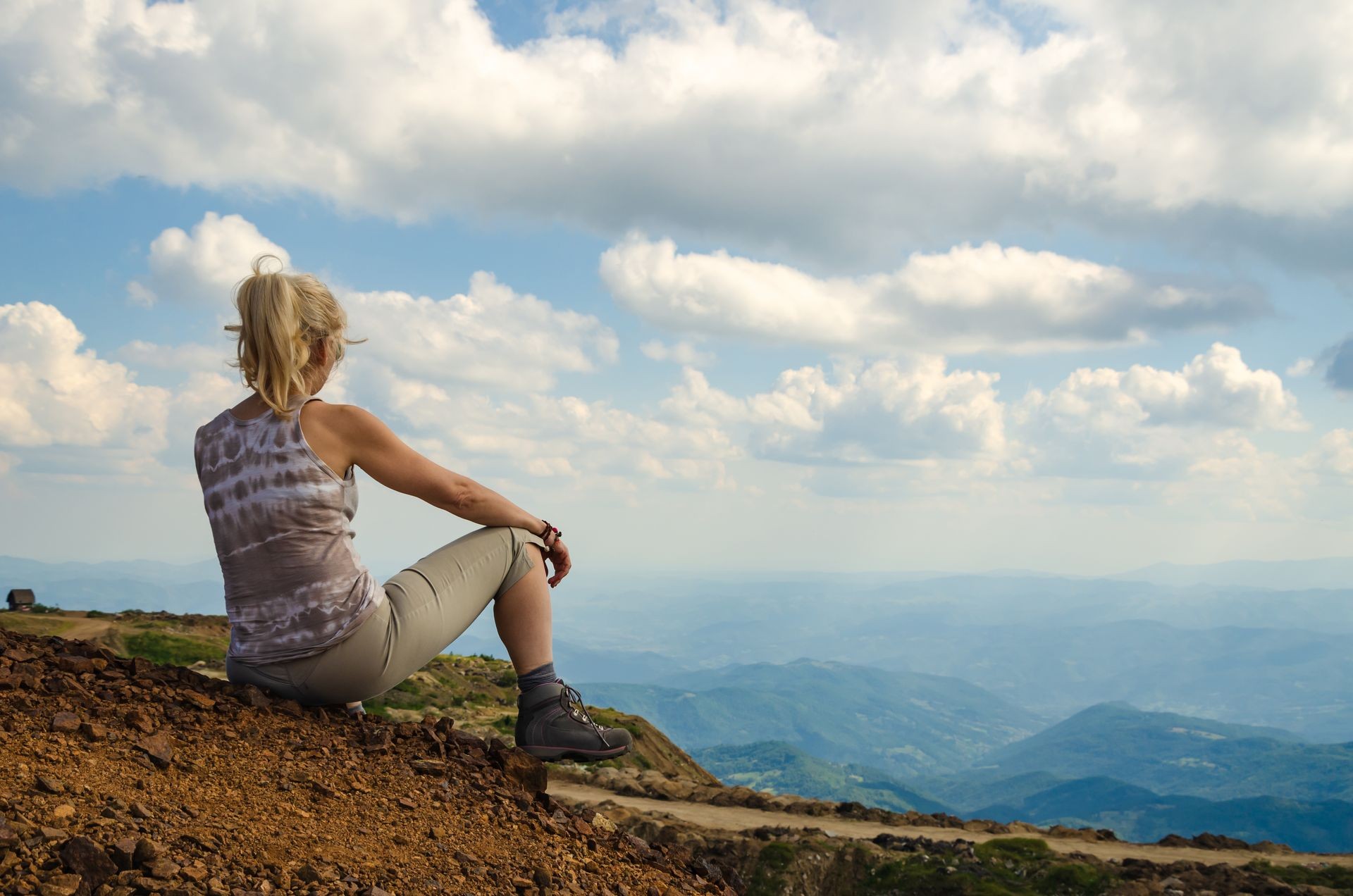 Woman is taking breath on top of Kopaonik mountain and watching picturesque landscape